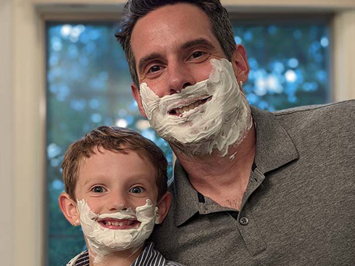 Man and child with shave cream on their faces, smiling