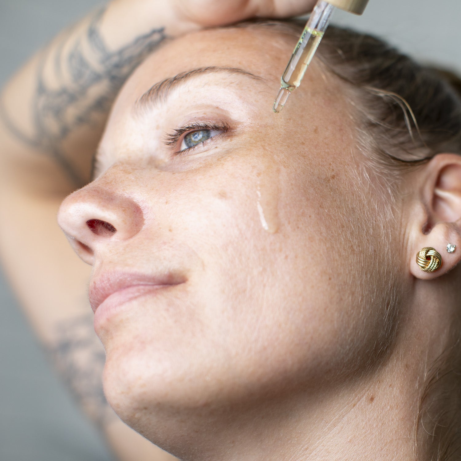 women tilting her head and dripping calming serum on her cheek