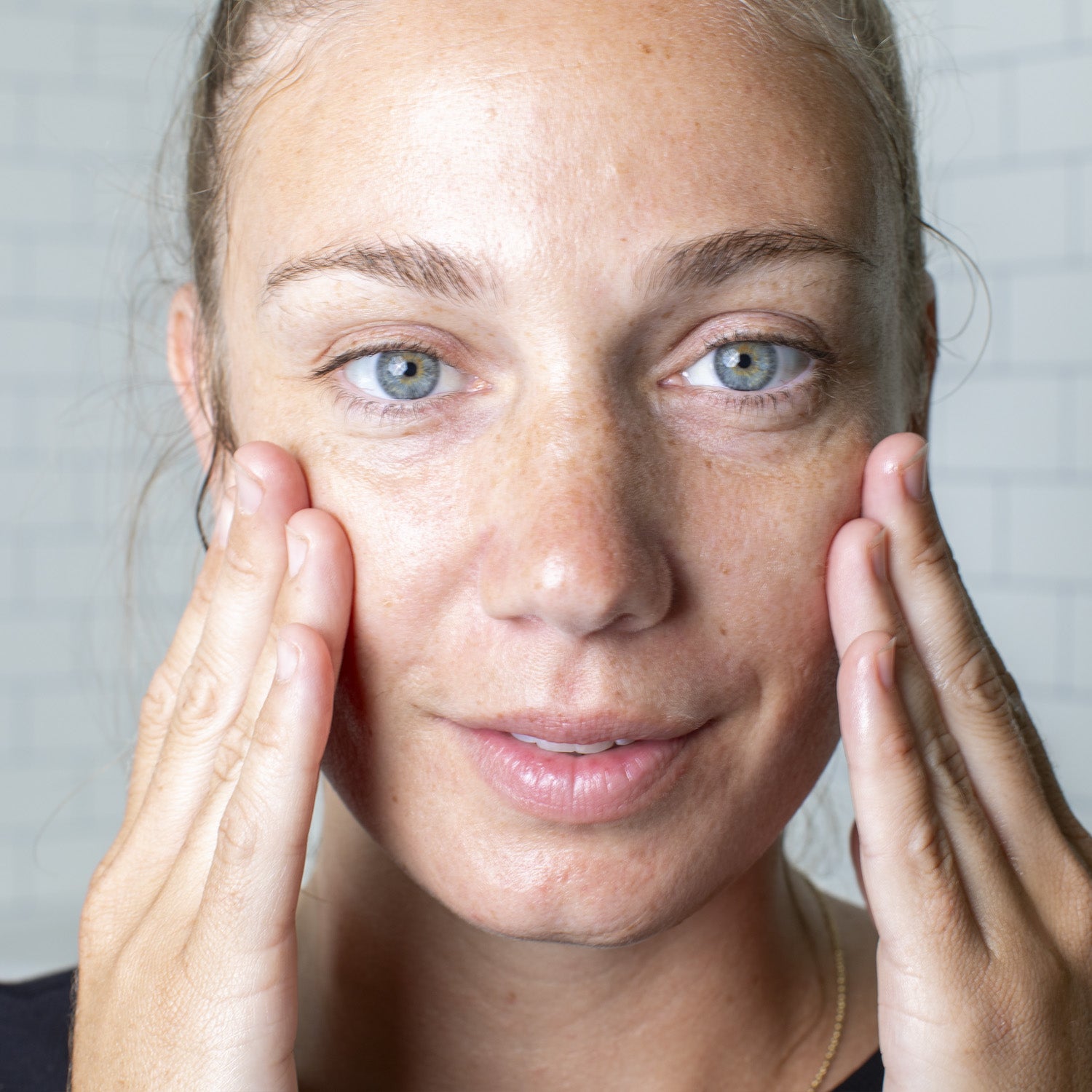 Women holding her hands against her cheeks, looking into the camera