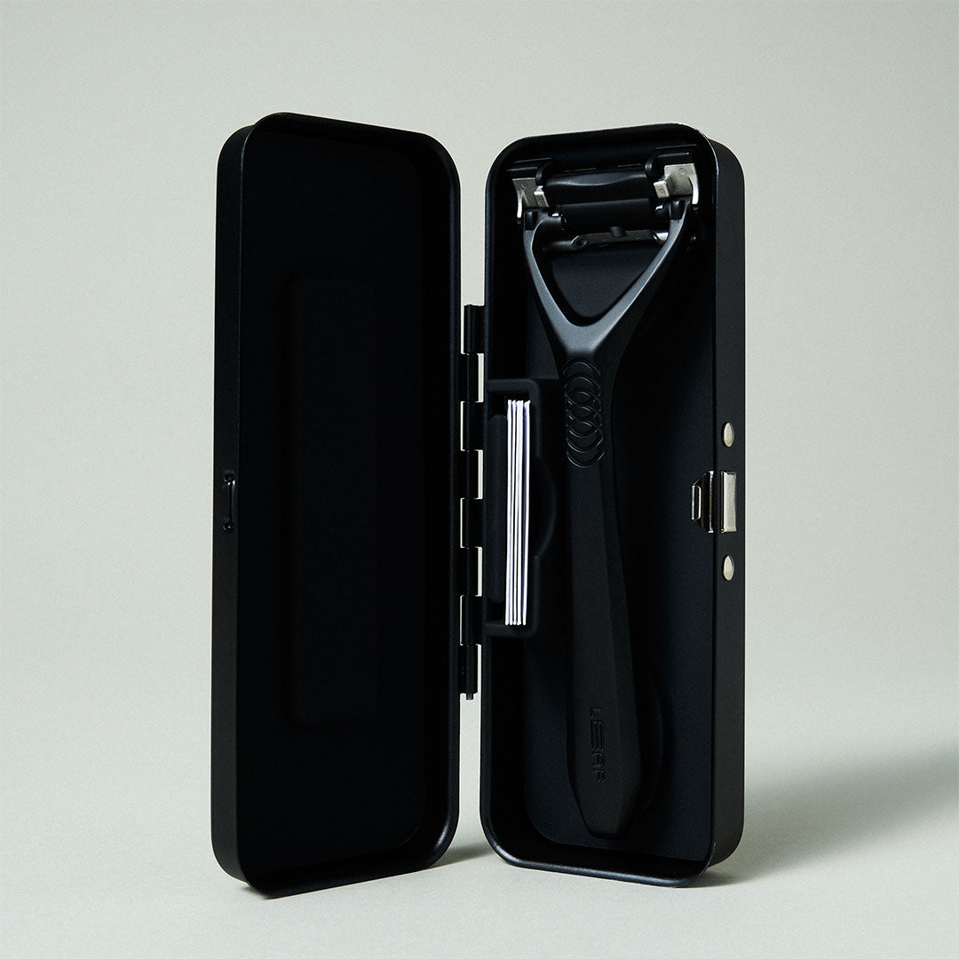 Black safety razor in an open black case on a light gray background