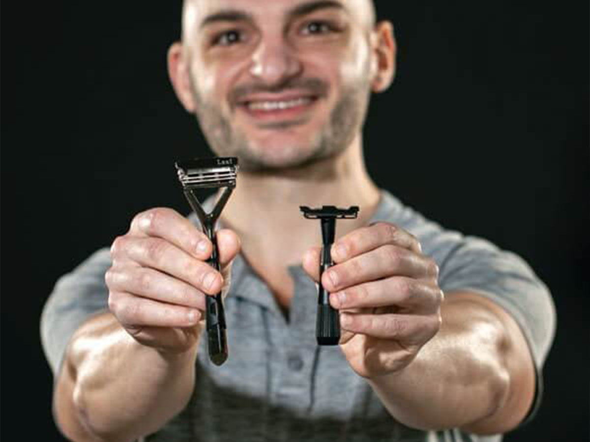 Man holding two razors outstretched
