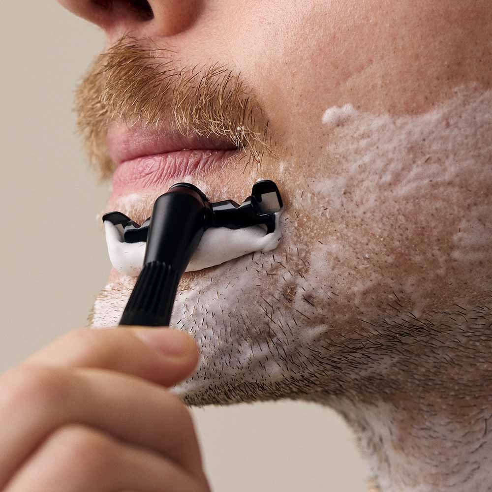 Man shaves his beard with the single edge razor