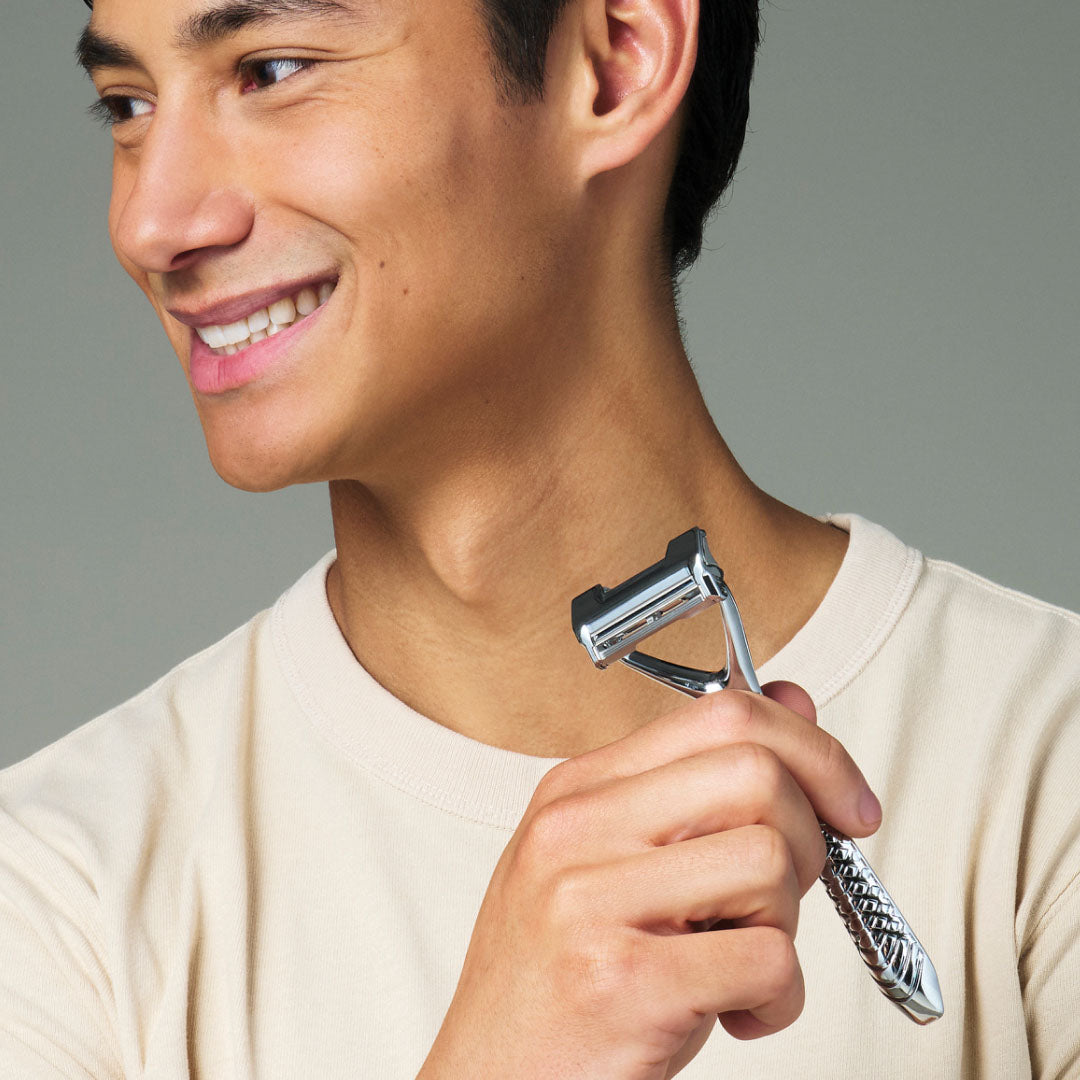 FACE Man holding a safety razor against his neck with a gray background