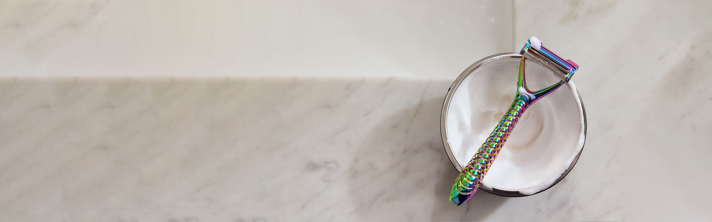 Multicolored razor on a white plate against a marble background