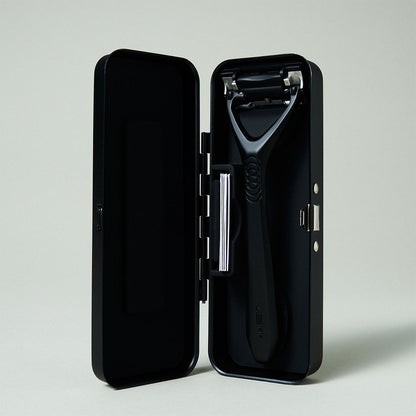 Black safety razor in an open black case on a light gray background