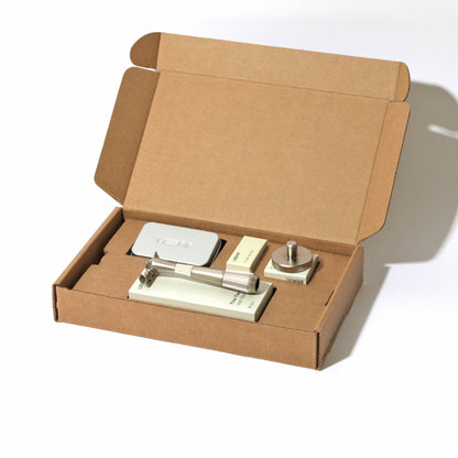 A kraft box on white, open, with a single-edge razor kit displayed in the finish called Silver